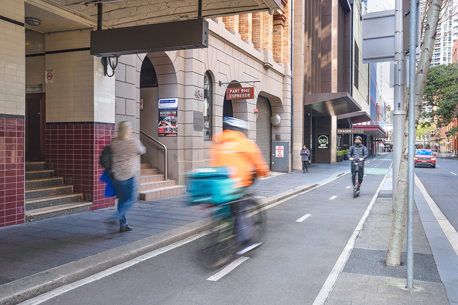 A cyclist and a scooter travelling on the new Kent Street, Sydney CBD cycleway.