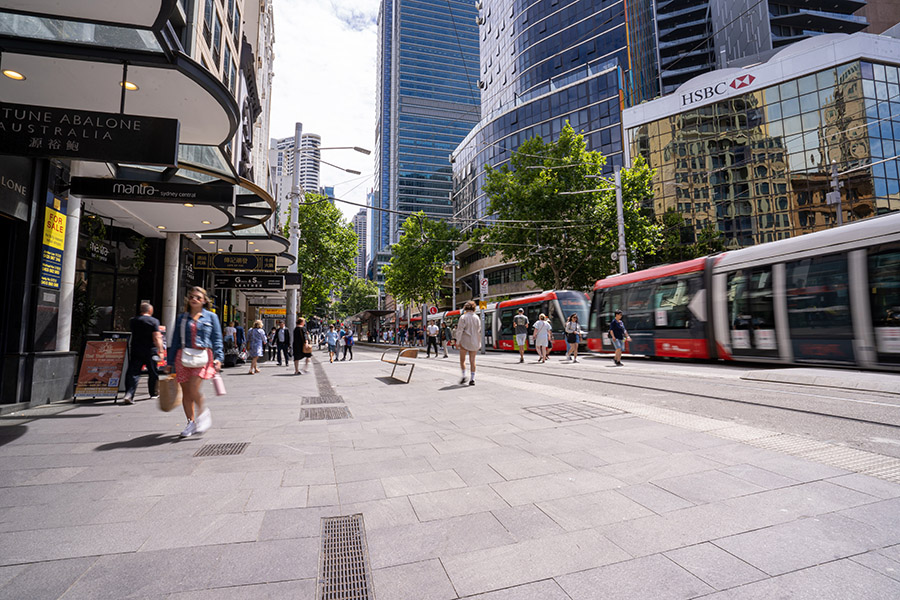 People embark and disembark trams at a stop along George Street in the Sydney CBD.