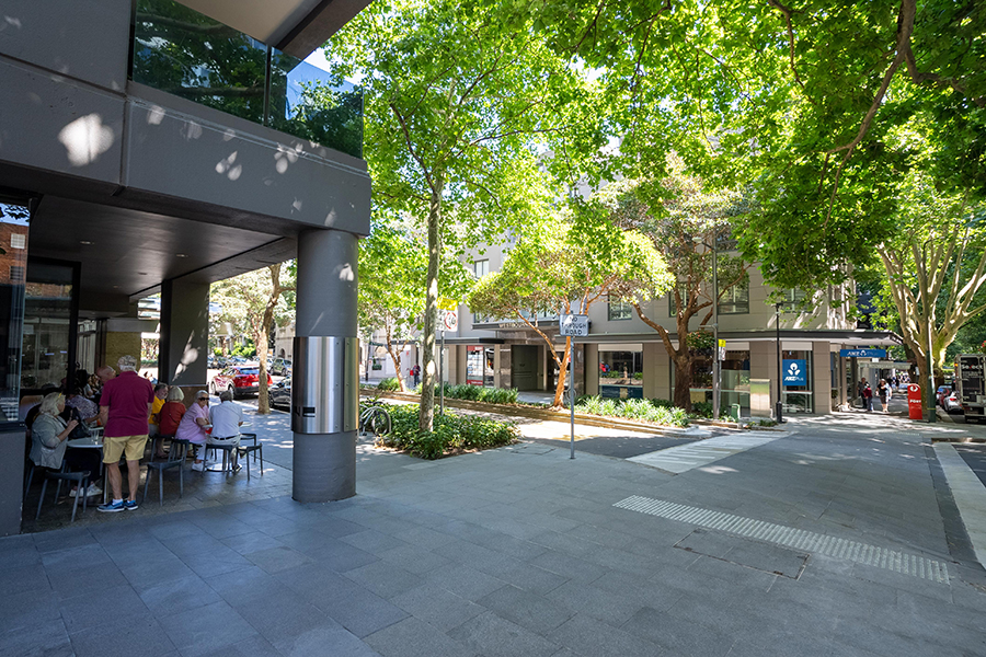 The start of the new Macleay Street streetscape, outside of a café and bank and shaded by trees.