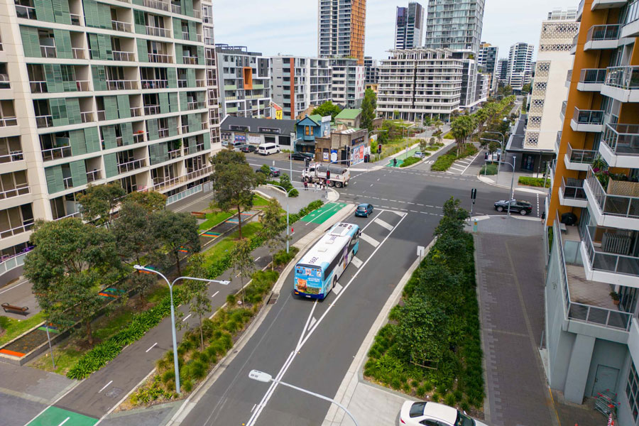A bus approaches the new intersection at Lachlan Street and Gadigal Avenue, landscaping visible.